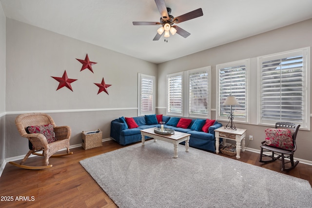 living room featuring a ceiling fan, baseboards, and wood finished floors