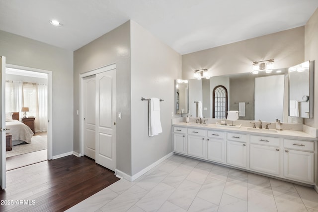 bathroom featuring double vanity, a sink, and baseboards