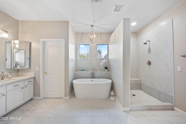 full bath with visible vents, walk in shower, a freestanding bath, vanity, and a chandelier