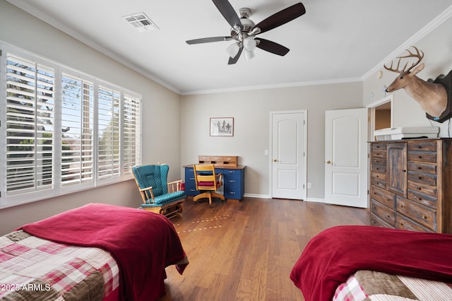 bedroom featuring visible vents, ornamental molding, a ceiling fan, wood finished floors, and baseboards