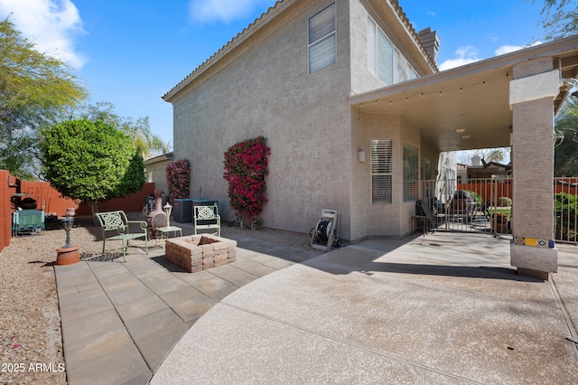 back of property featuring an outdoor fire pit, a patio area, fence, and stucco siding