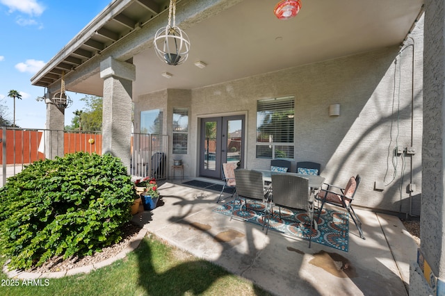 view of patio / terrace with french doors, outdoor dining space, and fence