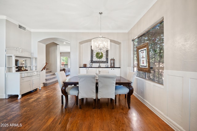 dining room with crown molding, stairs, visible vents, and wood finished floors