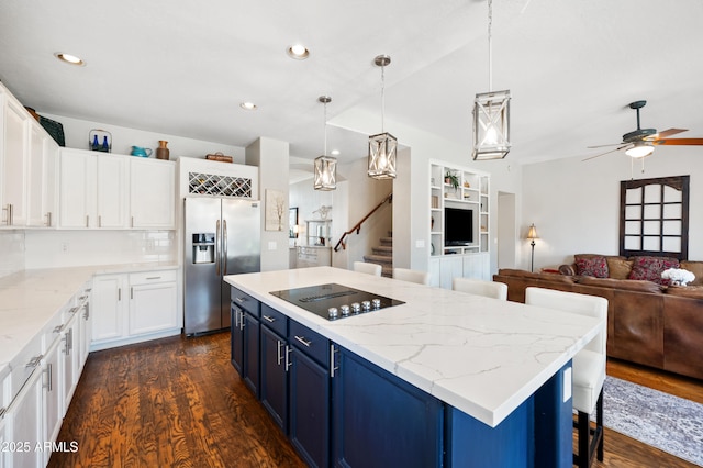 kitchen featuring blue cabinets, dark wood-style floors, stainless steel fridge, and black electric stovetop