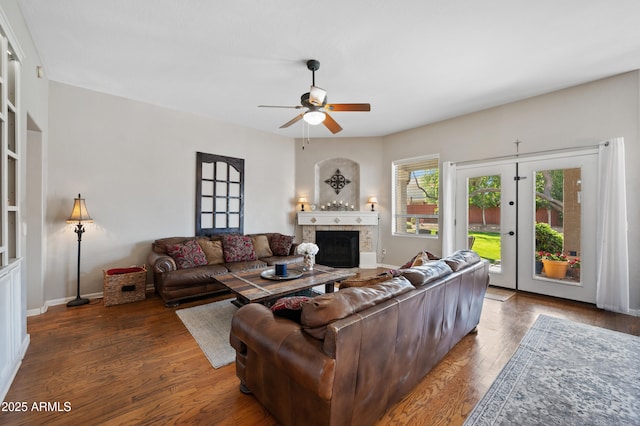 living room with baseboards, a ceiling fan, wood finished floors, and a tile fireplace