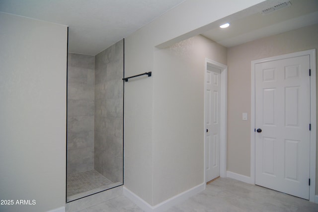 bathroom with baseboards, visible vents, and tiled shower