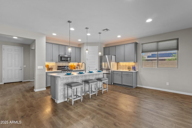 19203 W Jackson St, Buckeye, AZ 85326 - kitchen featuring appliances with stainless steel finishes, gray cabinets, backsplash, baseboards, and a breakfast bar