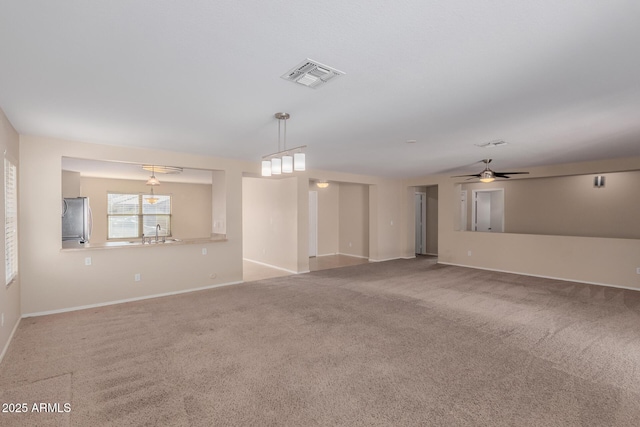 spare room with visible vents, baseboards, carpet floors, a ceiling fan, and a sink