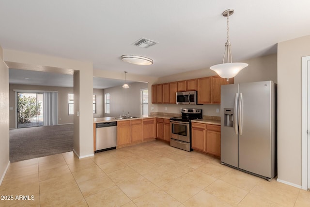 kitchen with visible vents, a sink, stainless steel appliances, light countertops, and hanging light fixtures