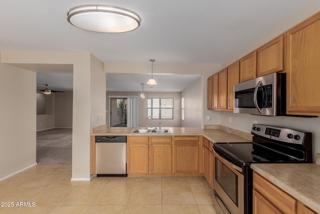 kitchen with light countertops, light tile patterned floors, appliances with stainless steel finishes, and a sink