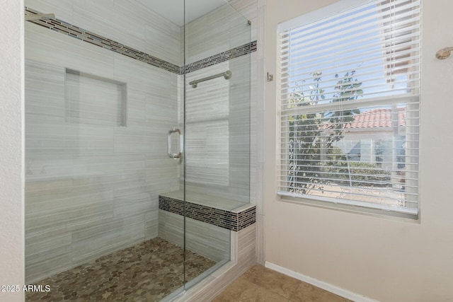 bathroom with tile patterned floors, baseboards, plenty of natural light, and a shower stall