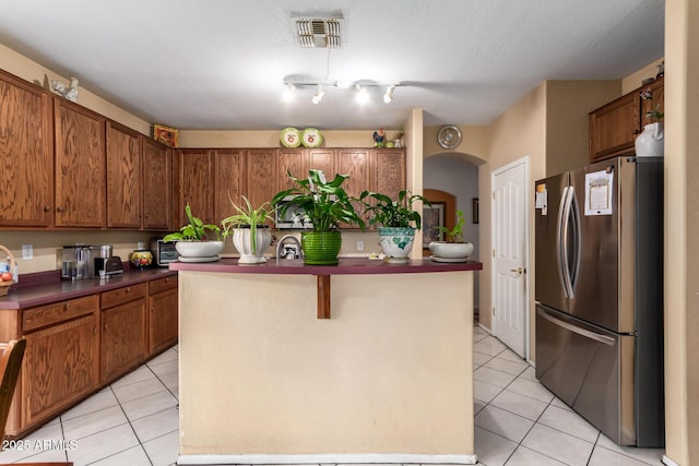 kitchen with freestanding refrigerator, a center island, visible vents, and light tile patterned floors