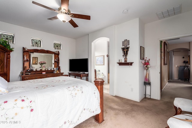 bedroom with arched walkways, carpet, visible vents, connected bathroom, and ceiling fan