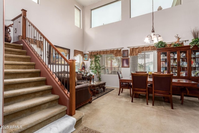 dining room with light carpet, stairway, and an inviting chandelier