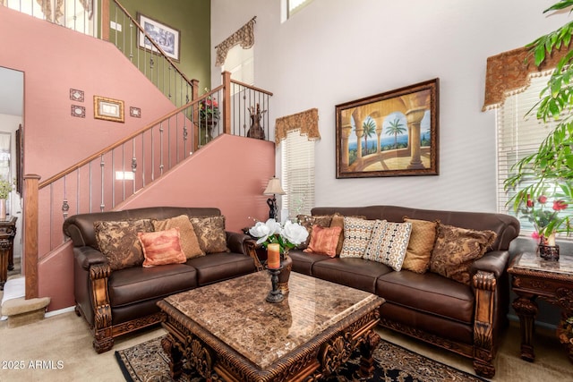 carpeted living area featuring a towering ceiling and stairs