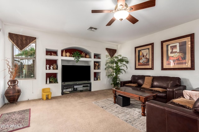 carpeted living room with ceiling fan, visible vents, and built in features