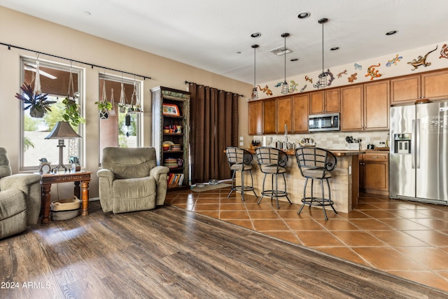 kitchen with pendant lighting, stainless steel appliances, a kitchen breakfast bar, a center island, and decorative backsplash