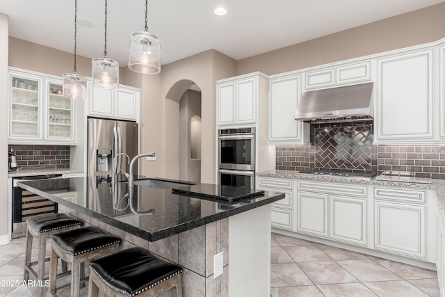 5428 E Windstone Trl, Cave Creek, AZ 85331 - kitchen featuring beverage cooler, under cabinet range hood, stainless steel appliances, a sink, and arched walkways
