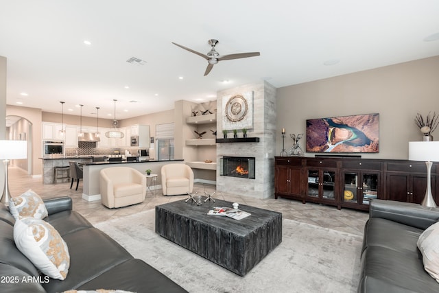 5428 E Windstone Trl, Cave Creek, AZ 85331 - living room featuring a ceiling fan, a tile fireplace, light tile patterned flooring, arched walkways, and recessed lighting