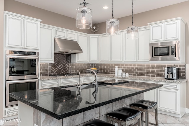 5428 E Windstone Trl, Cave Creek, AZ 85331 - kitchen with stainless steel appliances, under cabinet range hood, a kitchen bar, and decorative backsplash