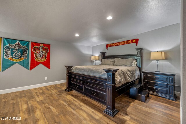 bedroom featuring a textured ceiling, hardwood / wood-style flooring, and a wall mounted air conditioner