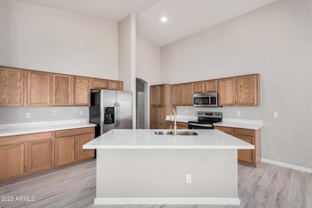13020 W Highland Ave, Litchfield Park, AZ 85340 - kitchen featuring stainless steel appliances, high vaulted ceiling, brown cabinets, a center island with sink, and light wood-type flooring