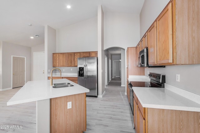 13020 W Highland Ave, Litchfield Park, AZ 85340 - kitchen with stainless steel appliances, arched walkways, light countertops, light wood-style flooring, and an island with sink
