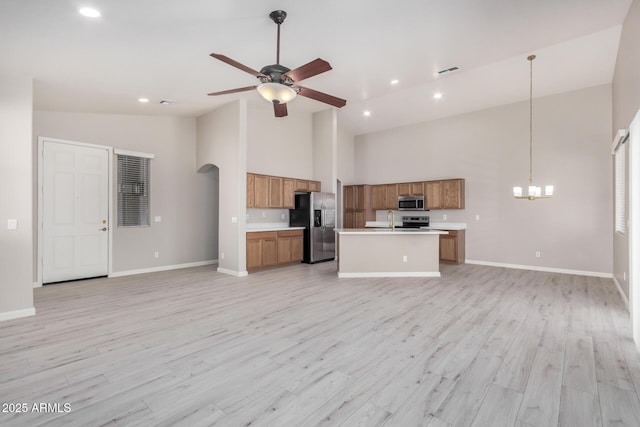 13020 W Highland Ave, Litchfield Park, AZ 85340 - kitchen featuring stainless steel appliances, open floor plan, brown cabinetry, high vaulted ceiling, and light countertops