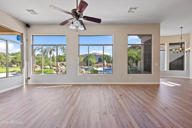 interior space featuring a wealth of natural light, wood-type flooring, and ceiling fan with notable chandelier