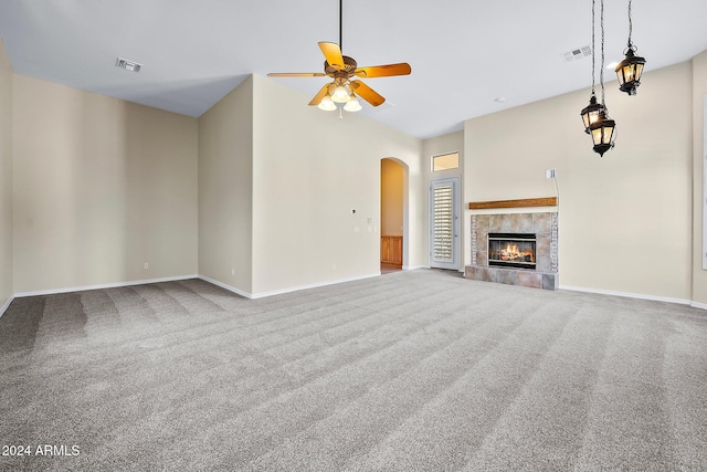 unfurnished living room with a tile fireplace, ceiling fan, and carpet