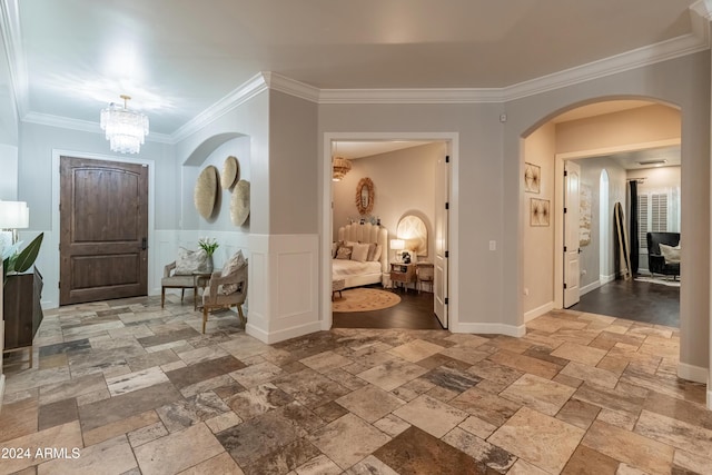 1409 E Dove Pl, Casa Grande, AZ 85122 - entryway featuring stone tile flooring, crown molding, a chandelier, arched walkways, and a wainscoted wall
