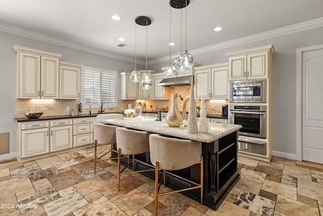 1409 E Dove Pl, Casa Grande, AZ 85122 - kitchen featuring cream cabinetry, appliances with stainless steel finishes, a warming drawer, under cabinet range hood, and decorative backsplash
