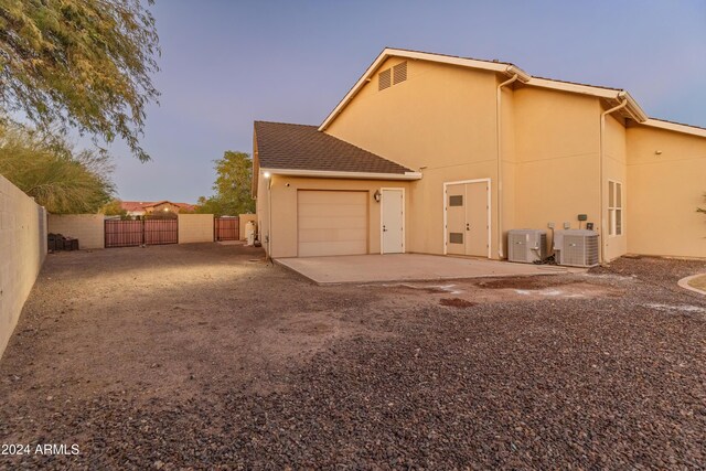 1409 E Dove Pl, Casa Grande, AZ 85122 - back of house featuring a garage, a gate, dirt driveway, stucco siding, and central AC