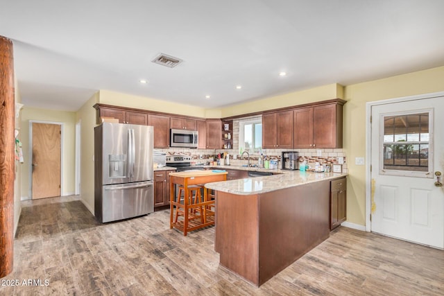 kitchen featuring a peninsula, light wood-style flooring, visible vents, and appliances with stainless steel finishes