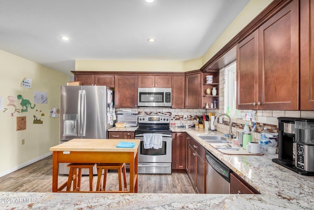 kitchen featuring a sink, open shelves, light wood-type flooring, and appliances with stainless steel finishes