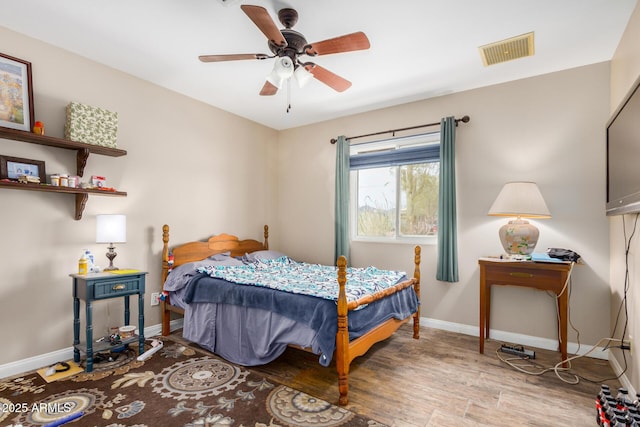 bedroom featuring visible vents, ceiling fan, baseboards, and wood finished floors