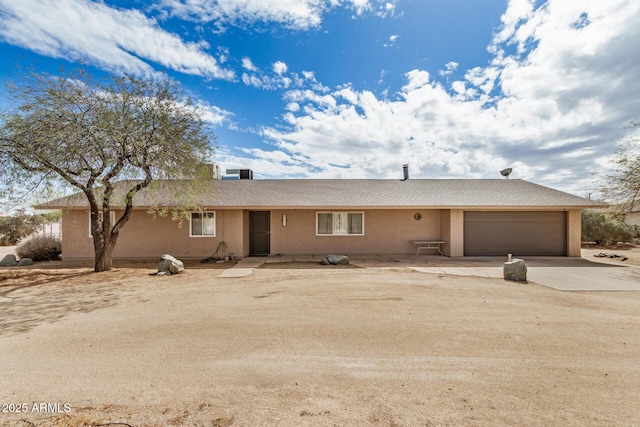 ranch-style home with stucco siding, an attached garage, and driveway