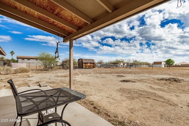 view of yard featuring an outdoor structure, a storage unit, fence, and a patio