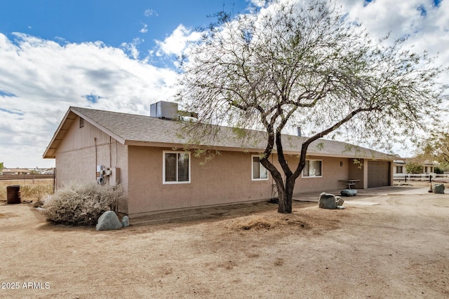 rear view of house with a garage and stucco siding