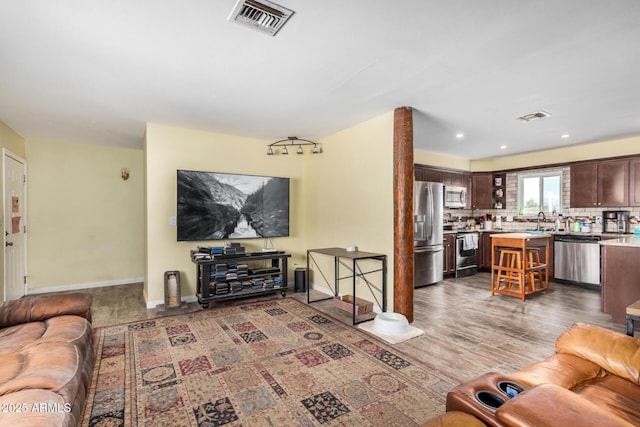 living area featuring recessed lighting, visible vents, baseboards, and wood finished floors