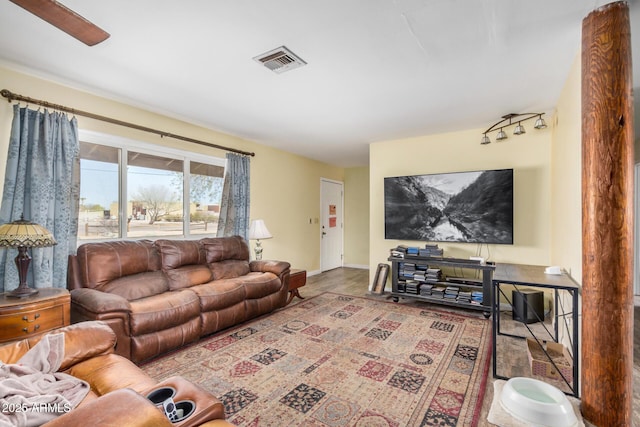 living area with a ceiling fan, wood finished floors, visible vents, and baseboards