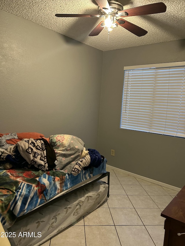 tiled bedroom featuring ceiling fan and a textured ceiling