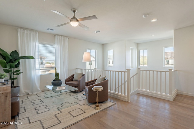 sitting room featuring an upstairs landing, visible vents, a ceiling fan, and wood finished floors