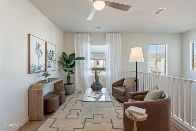 sitting room with wood finished floors, a ceiling fan, visible vents, and a wealth of natural light