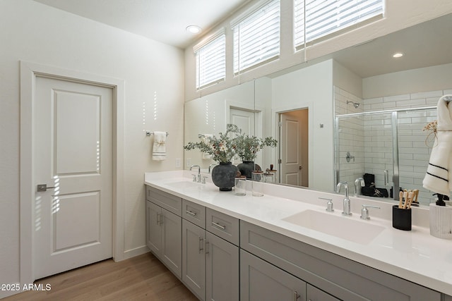 full bath featuring double vanity, a stall shower, wood finished floors, and a sink