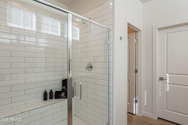 full bathroom featuring wood finished floors and a stall shower