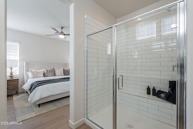 ensuite bathroom featuring a stall shower, a ceiling fan, ensuite bathroom, wood finished floors, and baseboards