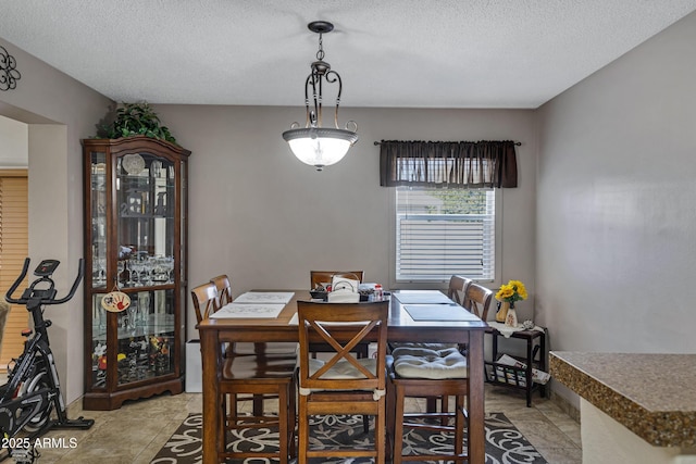 tiled dining room featuring a textured ceiling