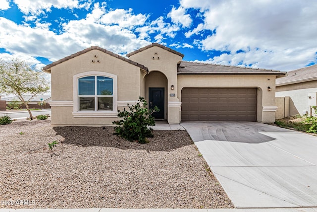 mediterranean / spanish house with a tile roof, stucco siding, an attached garage, and concrete driveway