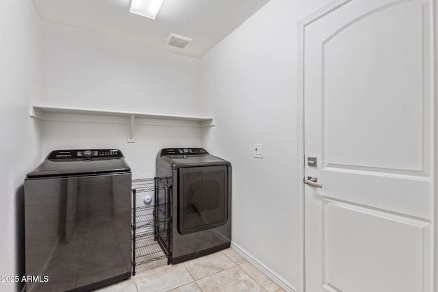 washroom featuring light tile patterned floors, visible vents, washer and dryer, laundry area, and baseboards